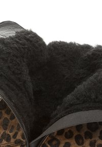 Interior de la bota con suave forro de felpa negra, detalle de cremallera y exterior de estampado de leopardo con un diseño texturizado.
