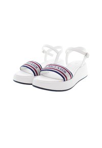 Bílé platformové sandály s nastavovacími pásky kolem kotníků. Mají pruhovaný textilní pásek s nápisem "U.S. POLO ASSN" v modré, červené a bílé barvě.