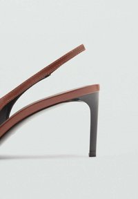 Ruske slingback pete sa šiljastim vrhom i visokim tankim crnim potplatima. Glatka kožna gornja seča sa minimalnim šavovima i elegantnim dizajnom.