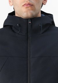Black jacket with a high collar and adjustable hood. Features a full zipper and no visible patterns. Made of a textured, durable material.