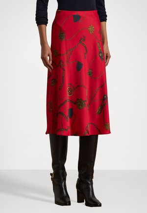 Red midi skirt with gold and blue patterned accents, smooth fabric, and a flowing silhouette, paired with black knee-high heeled boots.