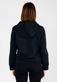 Felpa nera con cappuccio, dalla vestibilità rilassata, con una texture liscia e cuciture laterali. Polsini e orlo a costine, design semplice, senza motivi visibili.