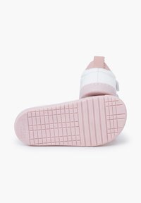 Sneaker bianco per bambini con suola e linguetta posteriore rosa, dotato di suola testurizzata e chiusura a strappo per facilitarne l'indossamento.