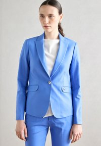 Svetle modrý přizpůsobený blazer s klopovým límcem, jednobotoným zapínáním a dvěma předními kapsami; hladká tkanina a úzký střih.