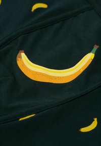 Tejido verde oscuro con grandes estampados de plátanos amarillos con tallos marrones y puntas verdes, junto con diseños de plátanos más pequeños esparcidos por todo el tejido.