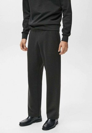 Pantalones gris oscuro de corte relajado, con cinturilla elástica y bolsillos laterales, combinados con mocasines negros. Tejido suave, sin patrones.