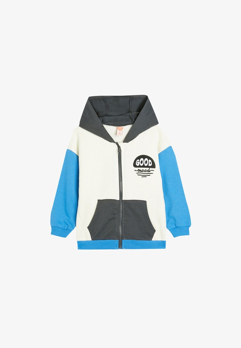 Chaqueta con capucha y cremallera en crema, gris y azul. Cuenta con bolsillos frontales, diseño de texto "GOOD", puños acanalados y una textura de tela suave.