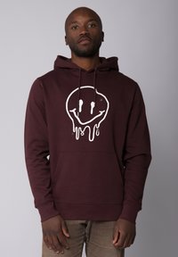 Bordeaux hoodie met een voorzak, voorzien van een witte druipende smiley-face grafiek. Gemaakt van zachte stof, heeft het een capuchon met trekkoord.