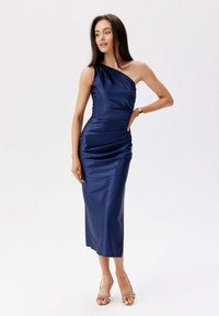 Jednoduché nazouvací šaty z námořnického saténu s nabíráním, s délkou ke kolenům a elegantním střihem. Disponují hladkým povrchem a minimálním zdobením.
