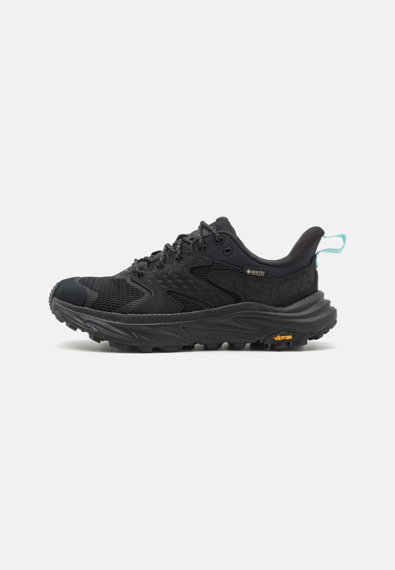 Pantofii de alergare negri cu partea superioară din plasă, accente texturate și talpă Vibram; au șireturi și un tab de tragere bleu deschis la călcâi.