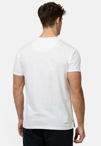 Hvid bomulds t-shirt med korte ærmer, rund hals og synlige sømdetaljer; glat tekstur og afslappet pasform.