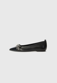 Chaussure plate en cuir noir à bout pointu, ornée d'une accent décoratif en métal à l'avant et d'une semelle plate.