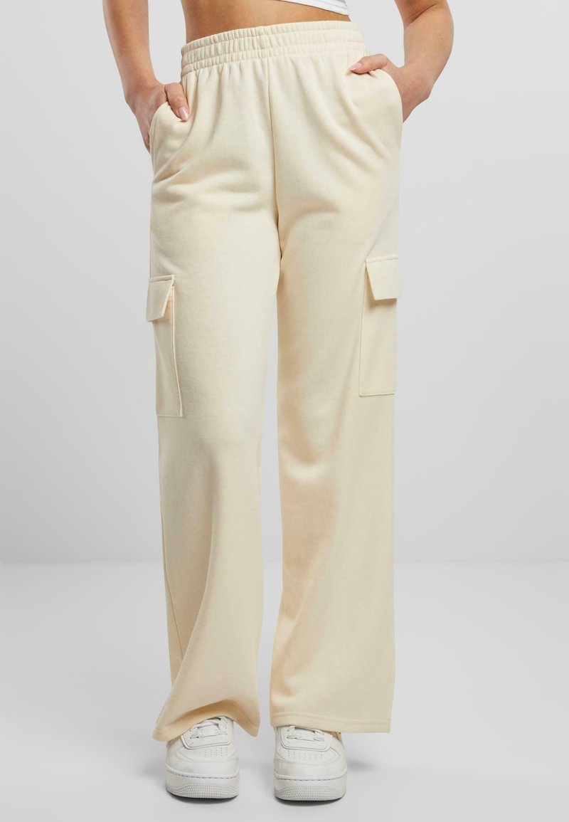 Pantalon cargo ample couleur crème en tissu doux, avec deux poches latérales et une ceinture élastique.