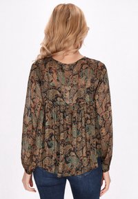 Bluză cu mâneci lungi, dintr-un material negru transparent, cu nuanțe de verde și rugină. Are un decolteu rotund și o talie strânsă.