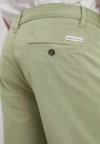 Light green shorts made of cotton, featuring back pocket, button closure, and a small Marc O'Polo label stitched on the waistband.