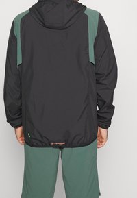 Czarna i zielona lekka kurtka z kapturem, elastycznymi mankietami i ściąganym dołem; posiada małe logo z tyłu oraz strukturalny materiał.