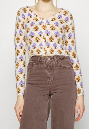 Cardigan lavorato a maglia con una base color crema che presenta motivi di funghi viola e marroni, bottoni rotondi e design a V; abbinato a pantaloni marroni.