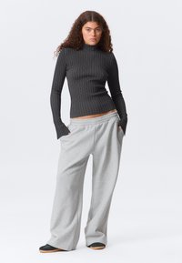 Μαύρο ριμπ ζιβάγκο μπλουζάκι με μακριά μανίκια και γκρι φαρδιά φαρδιά παντελόνια φόρμας με τσέπες, με ελαστική μέση και casual σχεδιασμό.