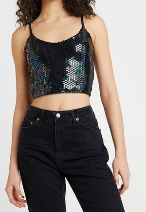 Pailletten crop top met dunne bandjes, versierd met meerkleurige ronde pailletten op een zwarte achtergrond; gedragen met hoge taille zwarte spijkerbroek.