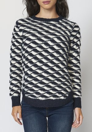 Navy and white patterned sweater features a knitted texture with a diamond wave design, round neckline, and ribbed cuffs and hem.
