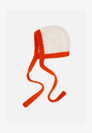 Balta megzta kepurė su oranžiniu apvadu, turinti du ilgus raištelius tvirtam užsegimui. Lygus paviršius su raštuotu dizainu.