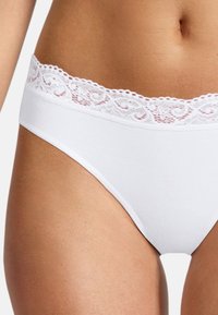 Weiße Baumwollunterwäsche mit einem Spitzenbund, die über eine glatte Textur und einen klassischen Hipster-Schnitt verfügt. Die Seitenansicht zeigt die Passform um die Taille.