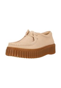 Beige Wildlederschuh mit runder Zehenpartie, Schnürdesign und einer dicken braunen Gummiplattformsohle mit vertikalen Rillen.