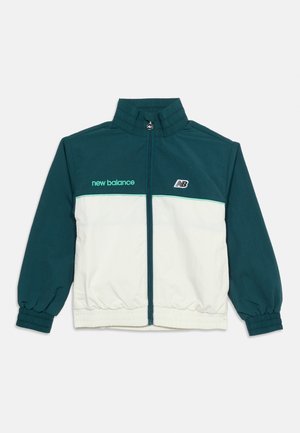 Veste de survêtement zippée intégrale, haut et manches coloris sarcelle, bas du corps blanc, poignets élastiques, texte "new balance" et logo "NB" sur la poitrine.