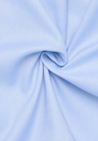 Tissu texturé bleu clair avec un motif tissé subtil, drapé et torsadé pour mettre en valeur sa douceur et sa surface lisse.