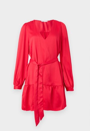 Rød kjole med lange ermer, dyp V-utringning og innsvingt midje. Laget av glatt stoff, med et lagdelt kant og matchende belte.