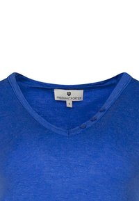 T-shirt bleu à col en V en tissu doux avec trois boutons au niveau du col. Étiquette de marque "FREEMAN T.P." visible à l'intérieur. Taille : S.