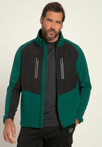 Zip-up jacka i svart och teal, tillverkad av mjukt tyg. Har två fickor med dragkedja på bröstet och en hög krage, med en figurnära design.