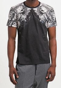 Svart t-shirt med ett mönstrat design i nyanser av grått och vitt på axlarna, med rund halsringning och korta ärmar.