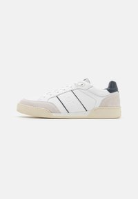 White leather sneaker with gray suede accents, navy detailing, and textured rubber sole. Features black stripes and embossed branding.