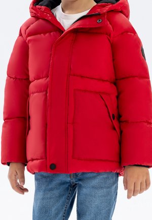 Veste rembourrée rouge avec capuche, dotée de grandes poches avant et d'accents noirs. Fabriquée à partir d'un matériau lisse et rembourré. Fermeture à bouton.