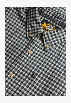 Geknoopte geblokte shirt in beige, zwart en blauw met een kraag, beige knopen en een "Regular Fit" label binnenin de kraag.