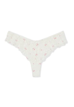 String blanc en dentelle avec petit motif floral rose et bords festonnés, présenté à plat sur fond blanc.