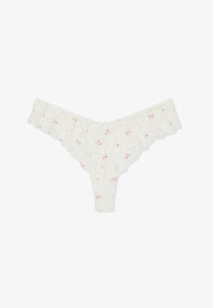 String blanc en dentelle avec petit motif floral rose et bords festonnés, présenté à plat sur fond blanc.