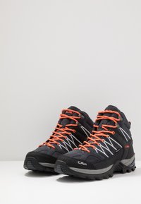 Schwarze Wanderschuhe mit orangen Schnürsenkeln und reflektierenden Akzenten. Hergestellt aus Stoff und synthetischen Materialien, mit einer strukturierten Sohle für besseren Grip.