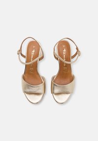 Gold metallic heeled sandals with a wide front strap and adjustable ankle strap. Features a smooth texture and brown insole labeled "37."