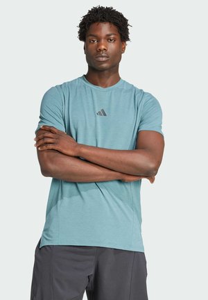 Turquoise athletic t-shirt in lightweight, breathable fabric. Features short sleeves, round neckline, and a printed logo on the chest.