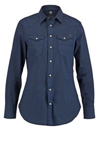 Chemise bleu marine à manches longues avec boutons, deux poches poitrine et boutons argentés, coupe droite avec col.