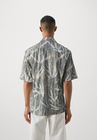 Short-sleeve, collared shirt in gray with a bamboo pattern. Features a relaxed fit and lightweight fabric.