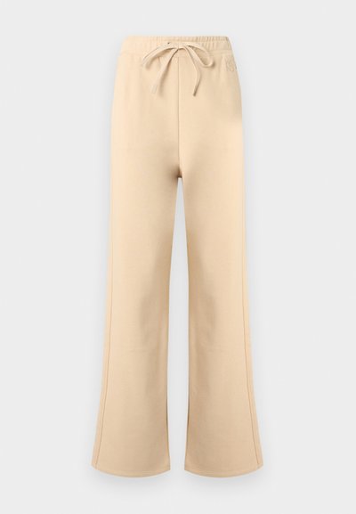 Μπεζ φαρδιά φόρμα με ελαστική μέση και κορδόνι, διακριτικές πλαϊνές ραφές και αχνό λ ογότυπο της μάρκας κοντά στη μέση.