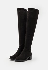 Botas negras por encima de la rodilla hechas de suave gamuza. Presentan un tacón cuadrado y una punta redondeada, con costuras elegantes y una suela de goma duradera.
