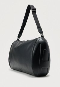 Czarna skórzana torba podróżna o gładkiej fakturze, zaokrąglonym kształcie i regulowanym pasku. Posiada wzmocniony boczny panel zapewniający trwałość.