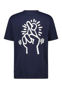 Camiseta de algodón azul marino con un gran gráfico en blanco de una mano cruzando los dedos, acentuado por rayos y líneas curvas alrededor del diseño.