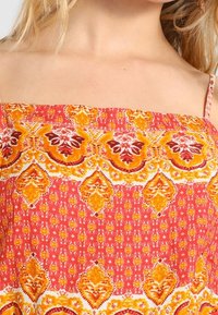 Vícebarevná, vzorovaná látka s květinovým vzorem v červených, oranžových a žlutých odstínech. Lehký materiál s hladkým povrchem.