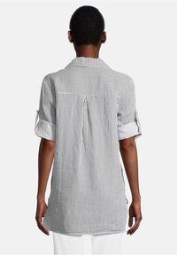 Camicia a righe grigia e bianca, con colletto, maniche arrotolate e una piega sul retro. Realizzata in tessuto leggero con vestibilità rilassata.
