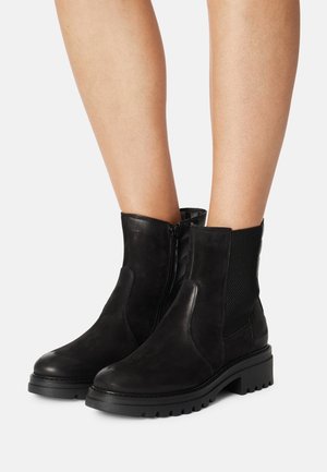 Botines negros de tobillo con un acabado de cuero suave, paneles laterales elásticos y suelas de goma con un patrón de relieve para mayor agarre.